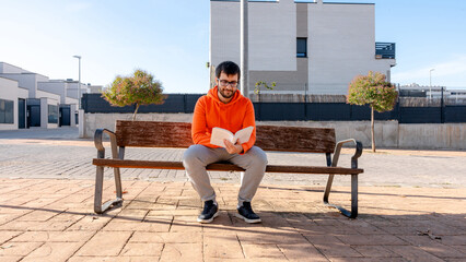 Man reading book on bench during a sunny day