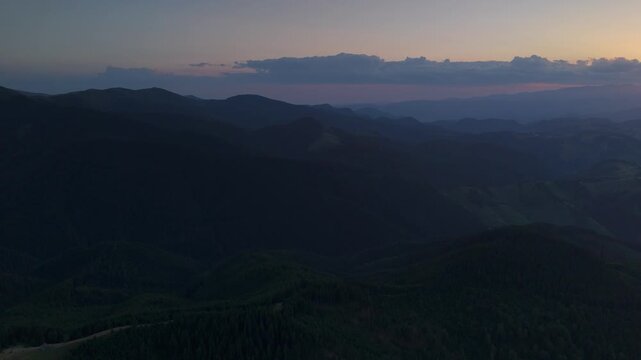 Wide 180 degree aerial panorama at the final moments of a summer sunset, layered mountain valleys and rolling hills fading into atmospheric haze, cinematic drone footage with serene mood, copy space