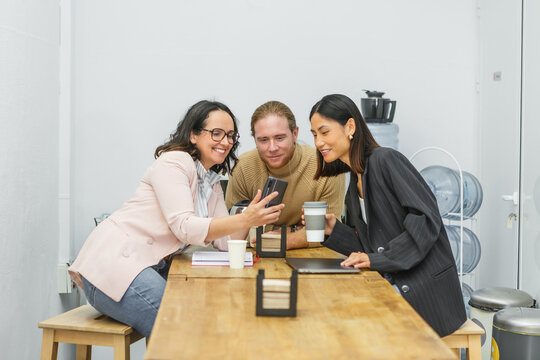 Team collaboration around smartphone in coworking space