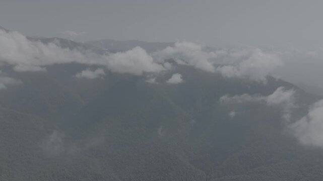 Majestic aerial drone view of white clouds and mountain mist moving over green forests with flat log profile, Azerbaijan