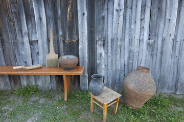 Objects of ancient village life near a wooden wall.