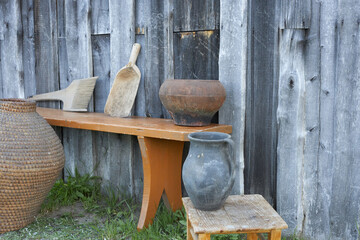 Objects of ancient village life near a wooden wall.