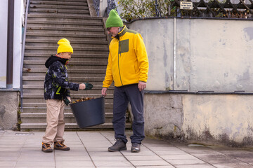 Boy assisting grandfather in garden leaf cleanup