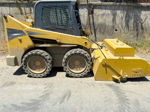 Compact yellow skid steer loader on construction site