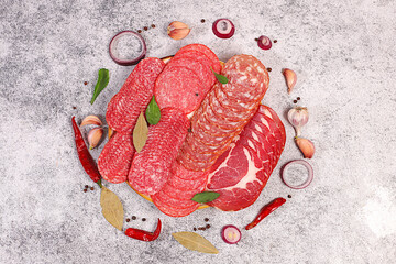 Delicious, aromatic appetizers of various salami cuts for the holidays. A selection of various smoked and dry-cured sausages and spices on a kitchen background. Advertising and menu for a store,