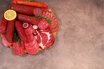 Selection of various smoked and dry-cured sausages, sliced salami, and spices on a kitchen counter. Advertising and menu for a store, banner for a cafe or restaurant. Delicious holiday appetizers