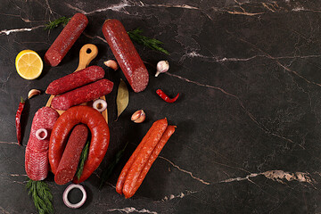 Selection of various smoked and dry-cured sausages, sliced salami, and spices on a kitchen counter. Advertising and menu for a store, banner for a cafe or restaurant. Delicious holiday appetizers