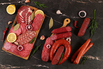 Delicious, aromatic appetizers of various salamis for the holidays. A selection of various smoked and dry-cured sausages and spices on a kitchen background. Advertising and menu for a store,