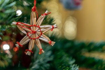 Christmas decoration hangs on a tree branch during holiday season in a home with warm lights and festive atmosphere