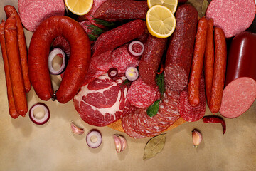 An assortment of various types of sausages, smoked meats, salami, and game sausages with lemon, spices, and herbs on a concrete table. Advertising and banner for a store, menu for a cafe or restaurant