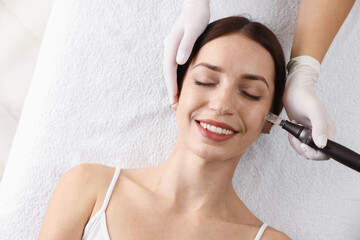 Woman undergoing microneedling procedure in beauty salon, top view