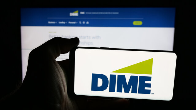 Stuttgart, Germany - 12-05-2025: Person holding mobile phone with logo of US financial company Dime Community Bank on screen in front of web page. Focus on phone display.