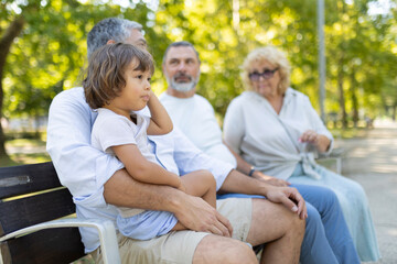 Obraz premium Multi-generational family sitting on park bench enjoying outdoor time