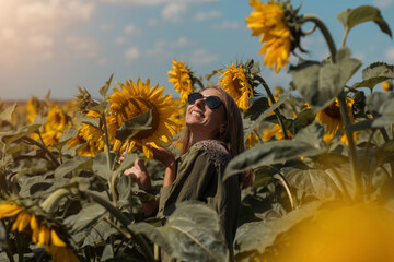 A girl in a pink skirt and a white T-shirt walks through a field of blooming yellow sunflowers. A woman dances, rejoices, smiles, enjoys life, warmth, summer, the sun. High quality FullHD footage