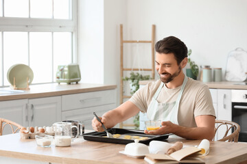 Young man preparing cookies in kitchen