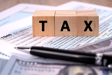 Income tax form and Tax word on wood block