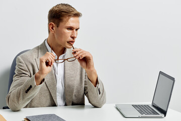 thoughtful man working laptop in beige jacket hold glasses thinking digital nomad remote work...