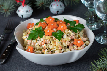 Olivier salad garnished with carrots and parsley in white salad bowl against a festive backdrop