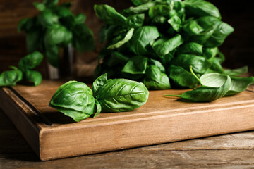 Board with fresh green basil leaves on wooden background, closeup