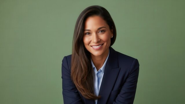 Confident professional woman with long brown hair wearing a navy blue blazer in front of a plain