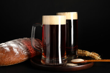 Mugs of tasty kvass, yeast and bread on black background