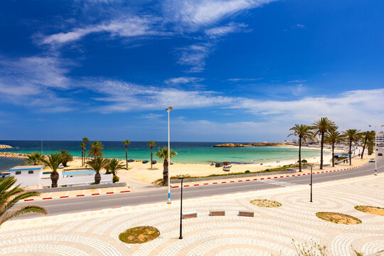 Coastal road with palm trees, beach and turquoise water in Monastir, northeastern Tunisia, on the Mediterranean Sea, travel background or wallpaper for your project