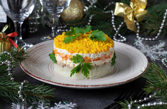 Puff salad Mimosa with canned fish, potatoes, cheese, carrots and eggs, garnished with parsley