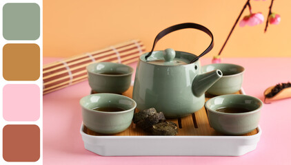 Tray with teapot, cups of tea, dry pressed puer leaves, bamboo mat and plum blossom branch on color background