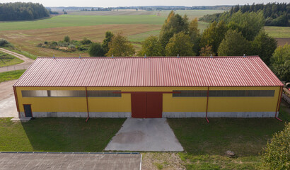 Sunny View of a Modern Yellow Agricultural Shed on Rural Farmland
