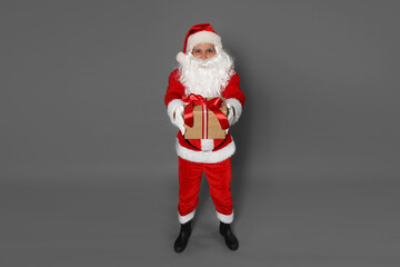 Santa Claus with Christmas gift on grey background