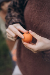 Close-up lifestyle photograph of hands peeling a fresh orange outdoors. Warm natural tones and...