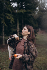 Lifestyle photo of a young woman walking in a forest holding a reusable mesh shopping bag with...