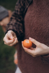 Close-up lifestyle photograph of hands peeling a fresh orange outdoors. Warm natural tones and...