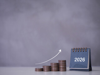 2026 desk calendar and stack of coins with arrow rising. The concept of business growth, Financial...