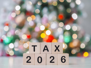 Wooden blocks with the word TAX and number 2026 with shiny light for Christmas background. The concept of prepare to pay tax in year 2026