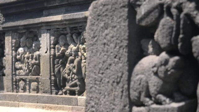 Beautiful ancient carvings depicting people and animals and decorating stone walls of Borobudur Buddhist temple in Magelang, Indonesia. Focus switches from foreground to background. Panning shot.