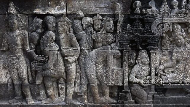 Close-up of gorgeous reliefs narrating Buddhist scriptures and adorning stone facades of Borobudur temple, Magelang, Central Java, Indonesia. World Heritage Site in details. Camera slowly zooms out.