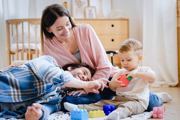 Young caucasian family of three, parents, mother and father playing developing games with toddler infant newborn baby son daughter at home, spending time together. Parenthood concept
