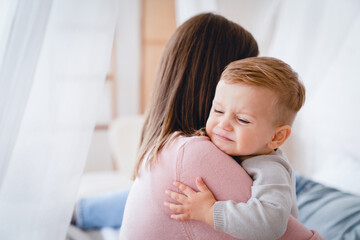 Caucasian mother lulling cradling her crying little small son daughter toddler infant newborn baby. Colics, teething health problems. Postnatal depression. Motherhood and childcare