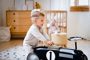Small little cute toddler kid child son daughter playing with toy car at home in playroom. Childcare and parenthood concept. Nurturing and nursery. Advertisement for children's products, clothing