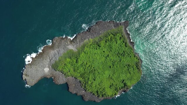 Smooth aerial capture of gentle waves breaking against the rocky shoreline of Limon Island.