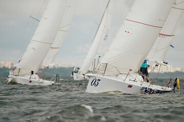 Naklejka premium bow of a sailing boats with bowsprit at sailing regatta in the Gulf of Finland at sunny day, sailing yacht competing in a race, splashing water from under the boat, teamwork, board the boat