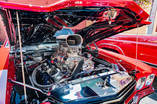 chrome engine of the Chevrolet Chevelle SS gleams under the open hood at a car enthusiast gathering.