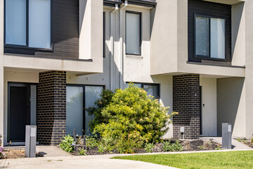 Modern suburban townhouse frontage in Melbourne, Australia, featuring compact mailboxes, small front yard. Medium-density housing design in new urban estates.