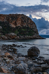 Rocky coastal cliff and calm sea under dramatic cloudy sky