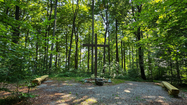 A wide angle of the wooden cross and benches for showing respect for the dead in the forest cemetery Friedwald Elisenruhe in Germany.