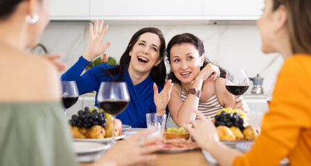 Girlfriends drinking wine and having conversation over dinner at a house party