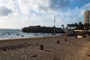 Wide sandy beach with calm sea and blue sky, coastal city on the horizon creating a peaceful seaside landscape with copy space.