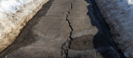 Crack in the road is shown with snow on the ground