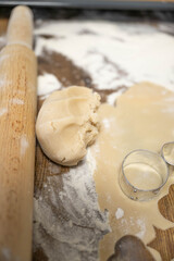 Homemade cookie baking process with dough, rolling pin and cutters. Step by step preparation of festive cookies on wooden table, cozy home kitchen, family baking concept.
